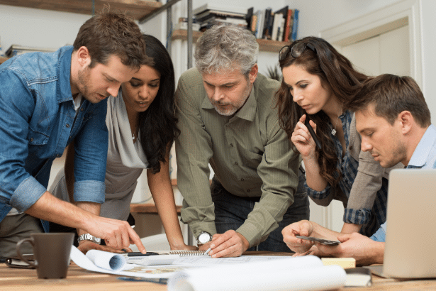 people close together looking at a piece of paper on an office table