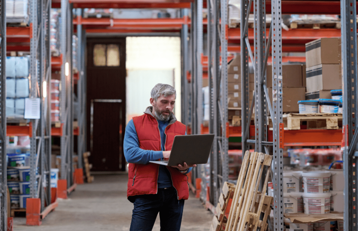 Man with laptop standing in warehouse